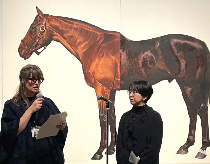 マーク・ウォーリンジャ―《半兄弟の競走馬（イグジットトゥノーウェアとマキャベリアン）》1994-95年（部分）、テート美術館蔵　と作品の前でプレス向けの解説をするテート・モダンのキュレーター Helen Little photo by APT